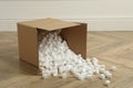 Overturned cardboard box with styrofoam cubes on wooden floor indoors Royalty Free Stock Photo