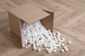 Overturned cardboard box with styrofoam cubes on wooden floor Royalty Free Stock Photo