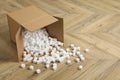 Overturned cardboard box with styrofoam cubes on wooden floor. Space for text Royalty Free Stock Photo
