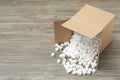 Overturned cardboard box with styrofoam cubes on wooden floor. Space for text Royalty Free Stock Photo