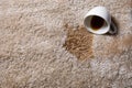 Overturned cup and spilled coffee on beige carpet, above view. Space for text Royalty Free Stock Photo