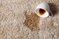 Overturned cup and spilled coffee on beige carpet, above view. Space for text Royalty Free Stock Photo