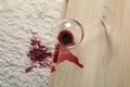 Overturned glass and spilled red wine on white carpet indoors, above view Royalty Free Stock Photo