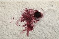 Overturned glass and spilled red wine on white carpet, top view Royalty Free Stock Photo