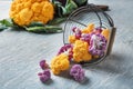 Overturned metal basket with colorful cauliflowers on light table