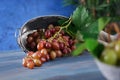 Overturned metal basket with fresh ripe grapes on wooden table