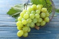 Overturned metal basket with ripe juicy grapes on wooden table