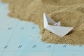 Overturned paper boat on a map with sand - Immigration concept Royalty Free Stock Photo