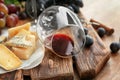 Overturned wineglass and cheese on wooden board, closeup