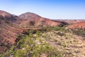 Overview of the MacDonnell ranges and the Larapinta trail from above. Red and orange mountains, dry season. Road crossing the West