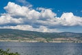 Overview of Okanagan lake with mountains and clouds on blue sky background.