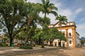 Overview of old colored church, garden with trees and cobblestone street in Paraty.