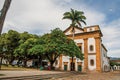 Overview of old colored church, garden with trees and cobblestone street in Paraty.