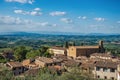 Overview of rooftops and church with green hills and blue sky at San Gimignano. Royalty Free Stock Photo