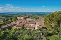 Overview of rooftops and church with green hills and blue sky at San Gimignano. Royalty Free Stock Photo