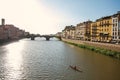 Overview of rower on the river Arno, bridge and buildings at sunset in Florence. Royalty Free Stock Photo