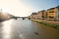 Overview of rower on the river Arno, bridge and buildings at sunset in Florence. Royalty Free Stock Photo