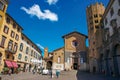 Overview of a square with old buildings, church and people under a blue sky in Orvieto.