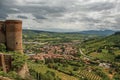 Overview of stone tower, green hills, vineyards and town rooftops near a road. From the city center of Orvieto.