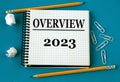OVERVIEW 2023 - word in a white notebook on a blue background with pencils, paper clips Royalty Free Stock Photo