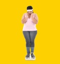 Overweight Asian woman looking shocked to see the weight on the scale Royalty Free Stock Photo