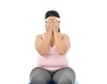 Overweight Asian woman sitting on a gym ball looking stressed covers her face with her hands isolated on white backgroun