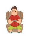 Overweight boy playing computer games and sitting in a soft chair. Royalty Free Stock Photo