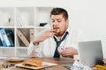 overweight businessman eating donuts, hamburger and french fries Royalty Free Stock Photo