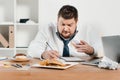 overweight businessman eating donuts, hamburger and french fries while wokring Royalty Free Stock Photo