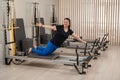 Overweight caucasian woman doing pilates exercises on a reformer.