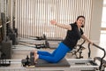 Overweight caucasian woman doing pilates exercises on a reformer.