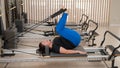 Overweight caucasian woman doing pilates exercises on a reformer.