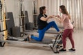 Overweight caucasian woman doing pilates exercises on reformer with personal trainer. Royalty Free Stock Photo