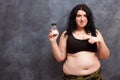 Overweight fat woman pointing on a bottle of slimming pills. Wei