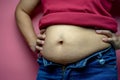 Overweight fat woman touching obese belly isolated on a pink background in Studio, closeup. Weight losing, obesity, cellulite, Royalty Free Stock Photo