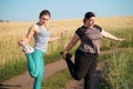 Overweight and fit women warming up before jogging
