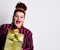 Overweight ginger female in striped dress, crown and earrings. Holding golden gift box, excited, posing isolated on white