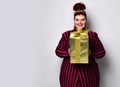 Overweight ginger female in striped dress, crown and earrings. Holding golden gift box, excited, posing isolated on white