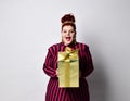 Overweight ginger female in striped dress, crown and earrings. Holding golden gift box, excited, posing isolated on white