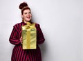 Overweight ginger female in striped dress, crown and earrings. Holding golden gift box, excited, posing isolated on white