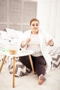 Overweight ginger lady checking her manicure while sitting on bed