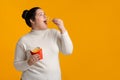 Overweight Girl Eating French Fries With Great Appetite Over Yellow Background