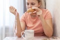 An overweight girl is eating a sandwich and holding a centimeter-long ribbon. Junk food. Royalty Free Stock Photo