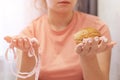 An overweight girl is eating a sandwich and holding a centimeter-long ribbon. Junk food. Royalty Free Stock Photo