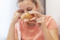 An overweight girl is eating a sandwich and holding a centimeter-long ribbon. Junk food. Selective focus Royalty Free Stock Photo