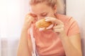 An overweight girl is eating a sandwich and holding a centimeter-long ribbon. Junk food. Selective focus Royalty Free Stock Photo