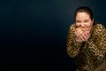 Overweight girl in a leopard blouse with a hamburger in her hand