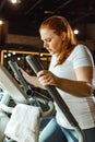 Overweight girl training on step machine in gym