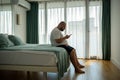 Overweight guy hanging in smartphone on resort sitting in bed in hotel room on vacation.