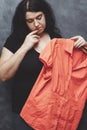 Obese shy woman hesitating to wear vibrant shirt